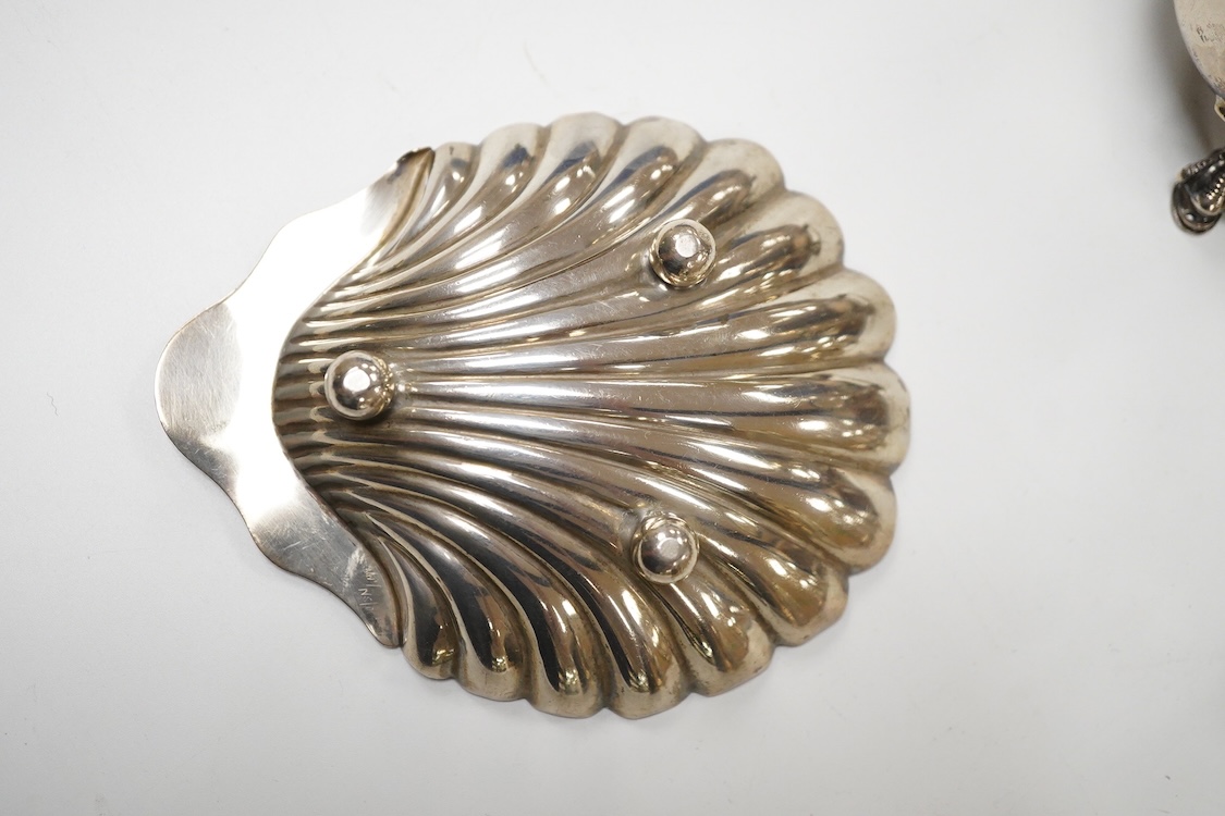An Edwardian silver mug, on claw and hoof feet, William Hutton & Sons, London 1909, height 83mm, together with a silver butter shell, mustard pot and a silver five bar toastrack, 17oz.